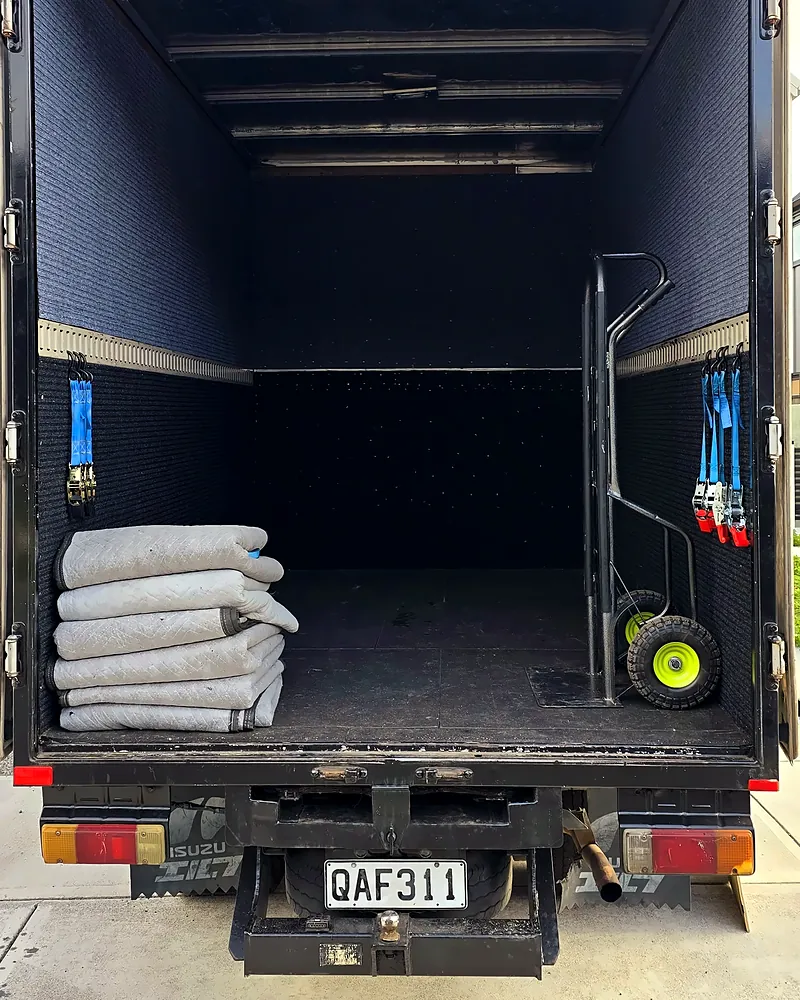Open truck with moving blankets and a hand trolley ready to load